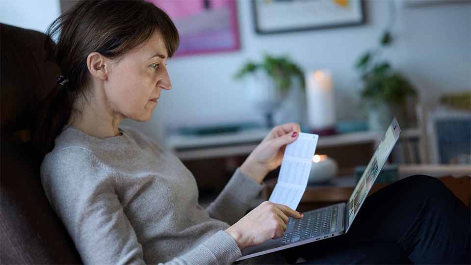Talblindhed giver problemer i skole og hverdag, men talblinde kan hjælpes Kvinde sidder i en stol og kigger koncentreret på en bærbar computer, mens hun holder et papir i hånden.