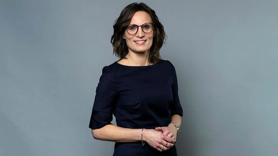 Jessika Roswall, EU-minister med ansvar för de nordiska frågorna, anser att det är viktigt att dela erfarenheter inom Norden för att stärka och utveckla utbildningssystemet. Foto: Kristian Pohl/Regeringskansliet Medelålders brunhårig kvinna med glasögon som ler mot kameran. Hon har en mörkt blå klänning med halvlånga ärmar på sig. Hon har några ringar, och armband på båda armarna. Hon är porträtterad mot en grå bakgrund.