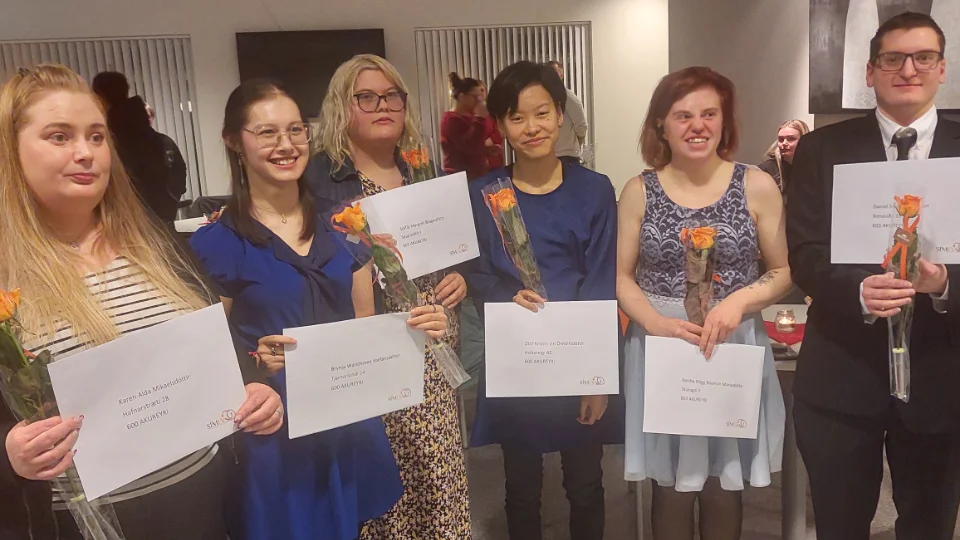 Det studenter fra Akureyri som mottar sine bevis En av deltakerne sitter foran en bærbar datamaskin ved et bord, konsentrert om skjermen, mens sollys strømmer inn gjennom vinduet bak henne.