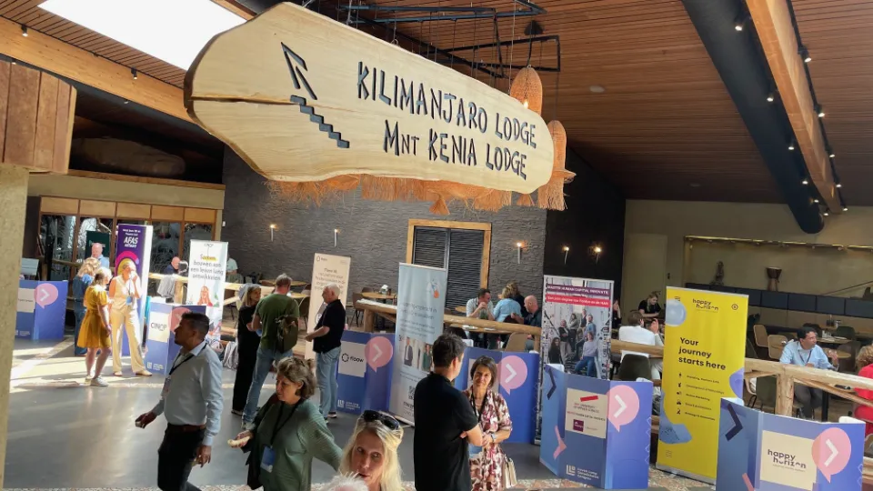 The Lifelong Learning Congress 2025 took place in Burgers’s Zoo in the city of Arnem in the Netherlands People networking and visiting exhibition booths at an indoor business event held at Kilimanjaro Lodge, with visible banners and informational displays.