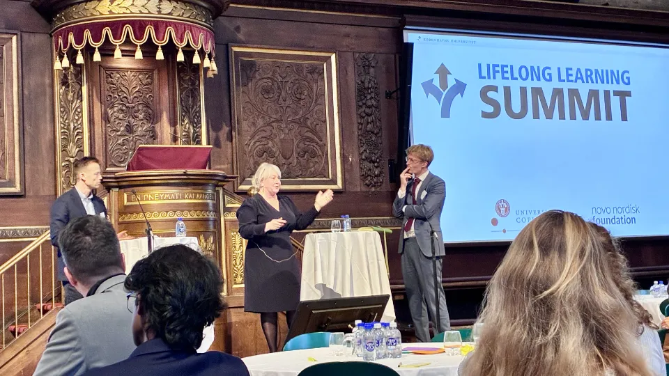 Christina Egelund holder oplæg ved Lifelong Learning Summit i København med publikum og medarrangører til stede.